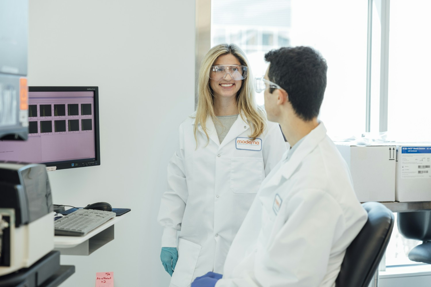 Two scientists collaborating in a state-of-the-art lab at Moderna's headquarters.