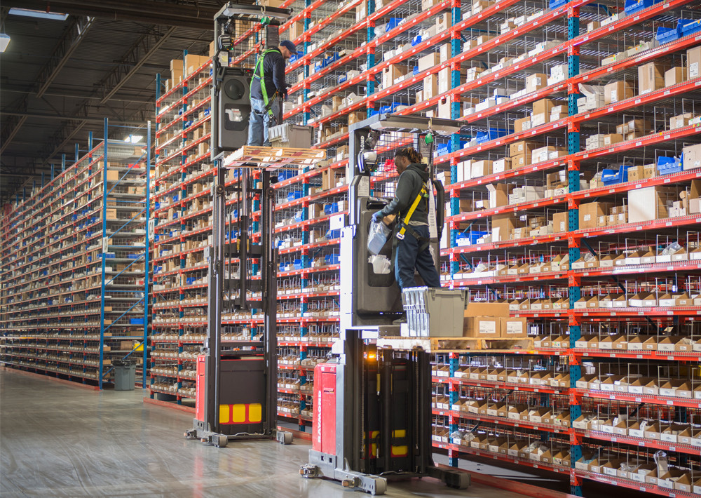 Order pickers using lifts in warehouse.