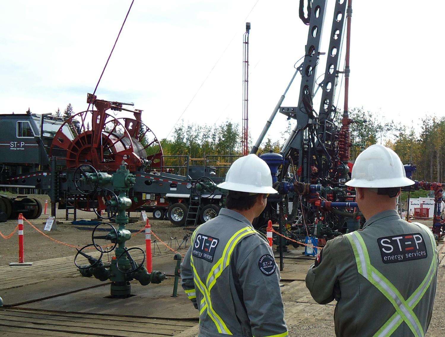 Professionals looking at a coiled tubing mast unit during a milling operation