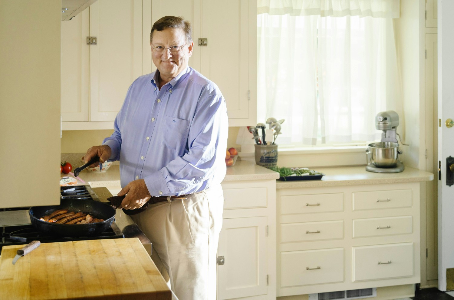 A training supervisor observing an employee inspect cooked sausage as it exits the oven.