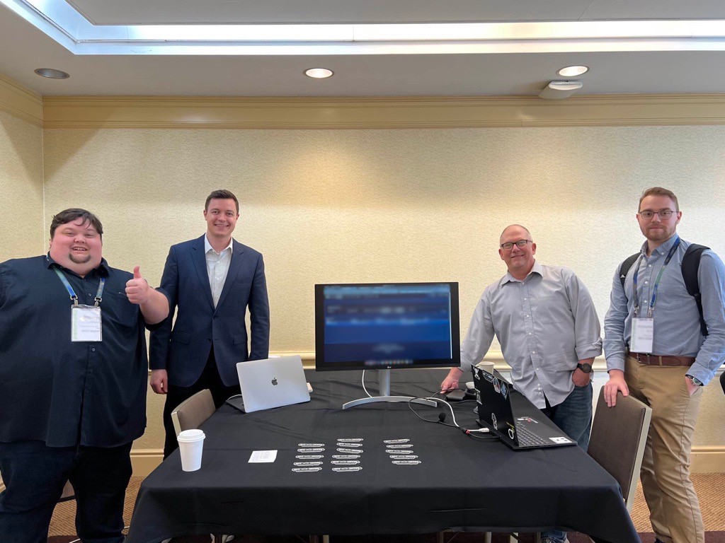 Some Threat Intelligence, Threat Operations, and Sales employees conducting product demos at a 2023 CTI conference.