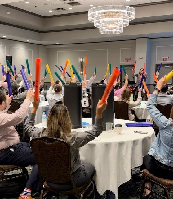 A speaker using percussion and rhythm to demonstrate the power of harmony and working in sync at our Managers' Meeting.
