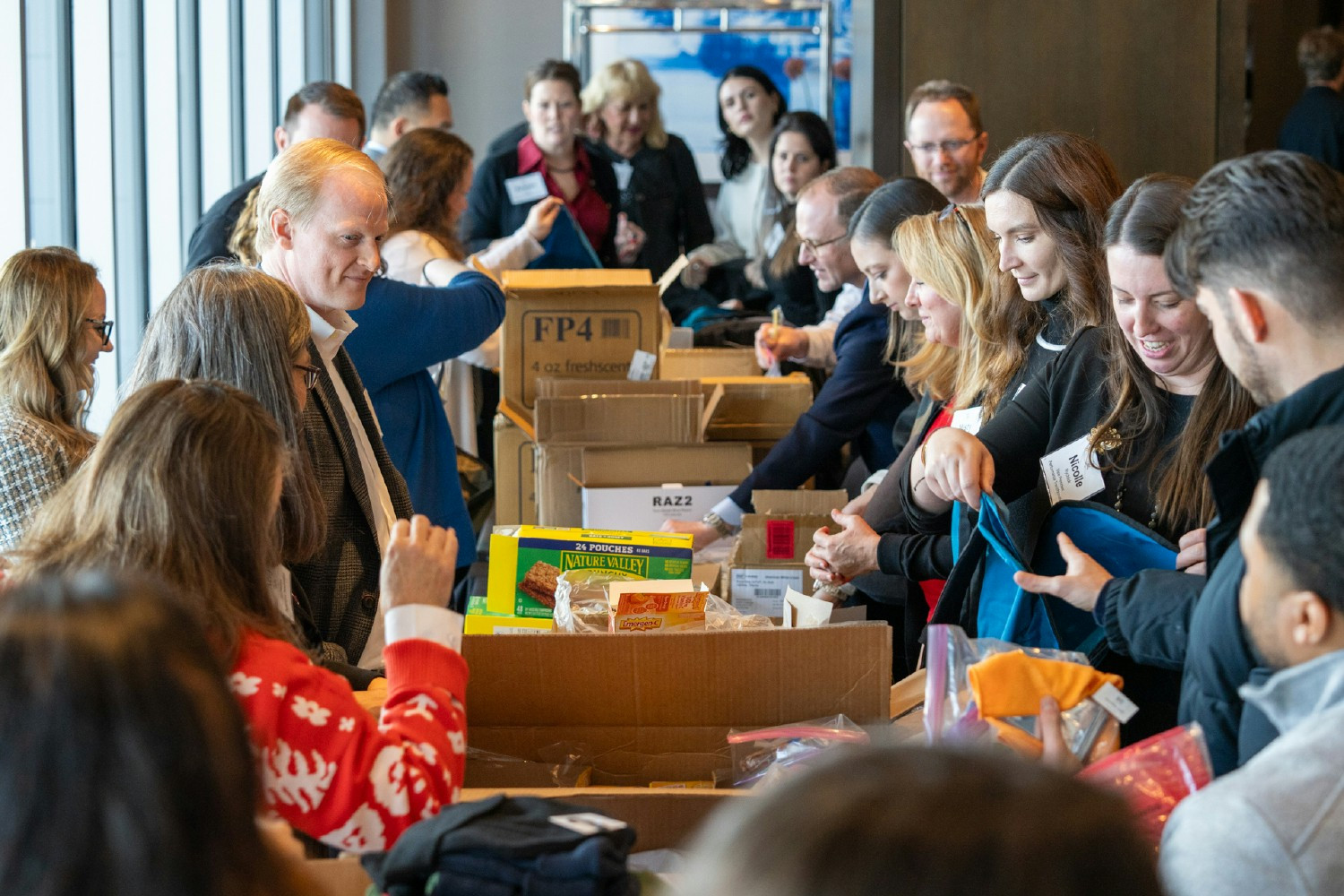 Team members packing backpacks with essential items as part of The Backpack Project community initiative.