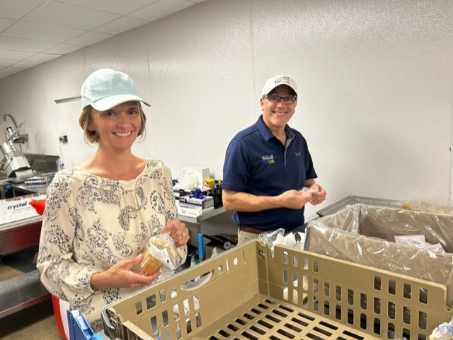 Top Line team members package food items at a volunteering event at Feed More