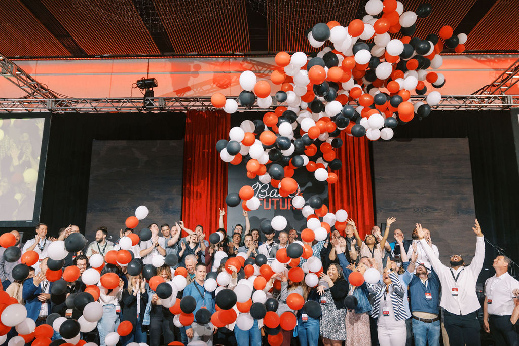 Fischer Homes associates celebrate together beneath a shower of red, white, and black balloons at the Annual Meeting.