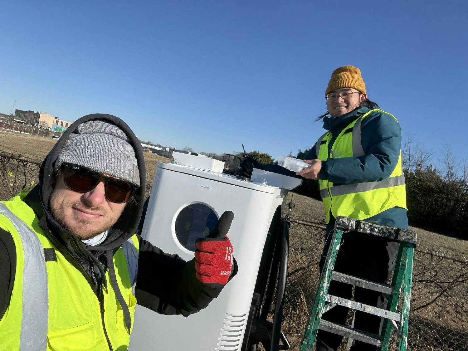 XCHARGE Energy North America - Team photo of Alex and Yan installing a C6 Charger while demonstrating use of PPE