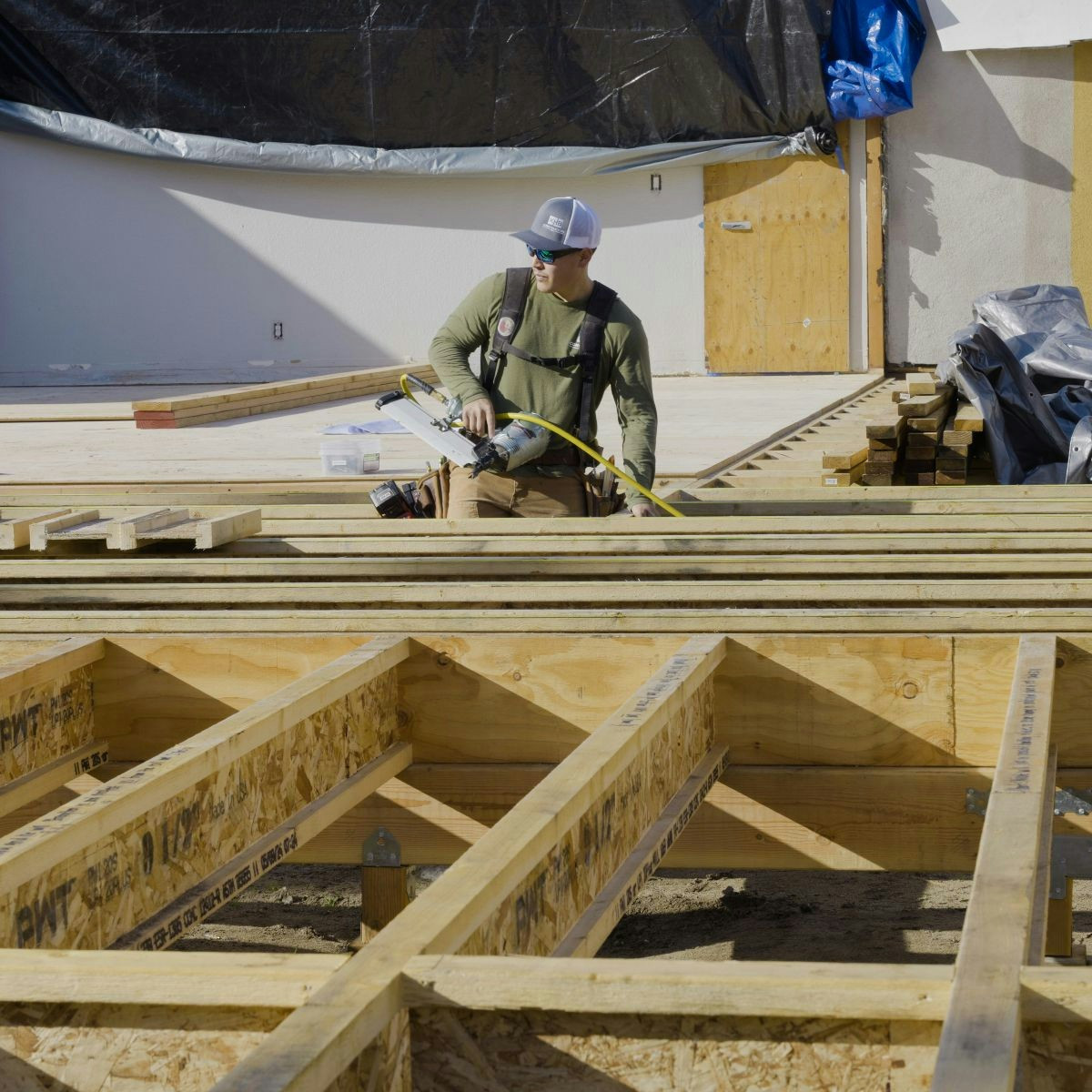 Crew member working through structural framing, highlighting hands-on craftsmanship and teamwork on site.