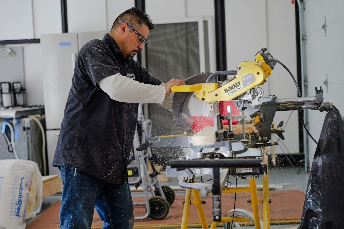 Crew member working with tools in the shop, focused on preparing materials for a project.