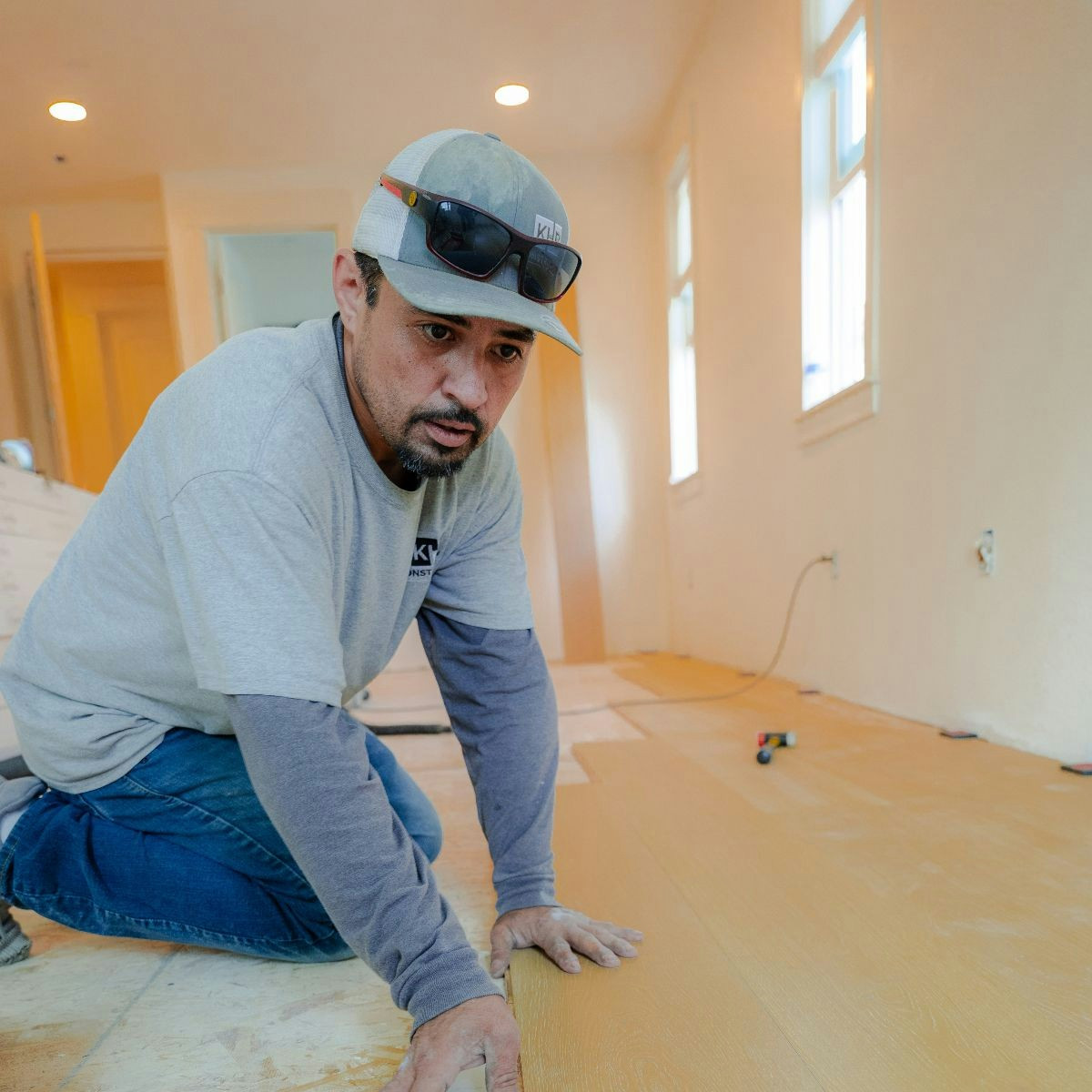 Crew member carefully placing wood materials on an interior jobsite as part of ongoing construction work.