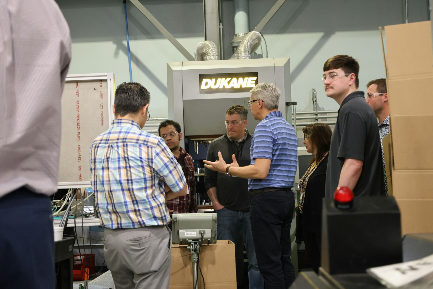Team members gather around advanced manufacturing technology to share ideas, solve problems and drive innovation.