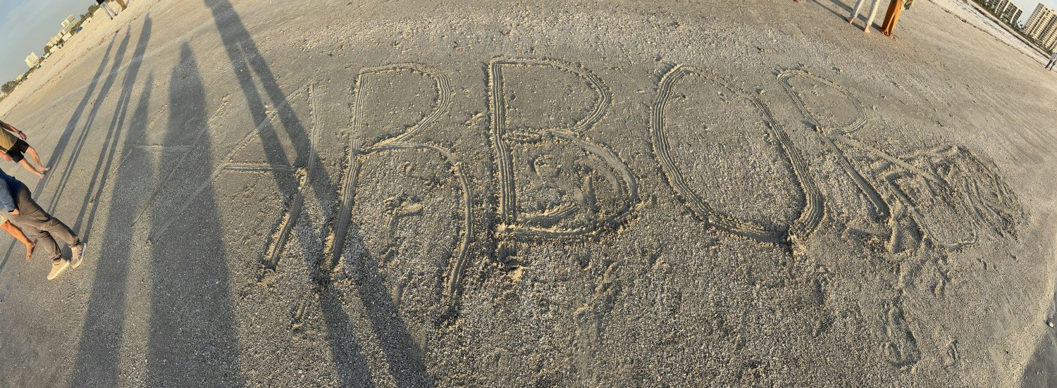 Company name drawn in the sand during company wide offsite in Florida. January 2026