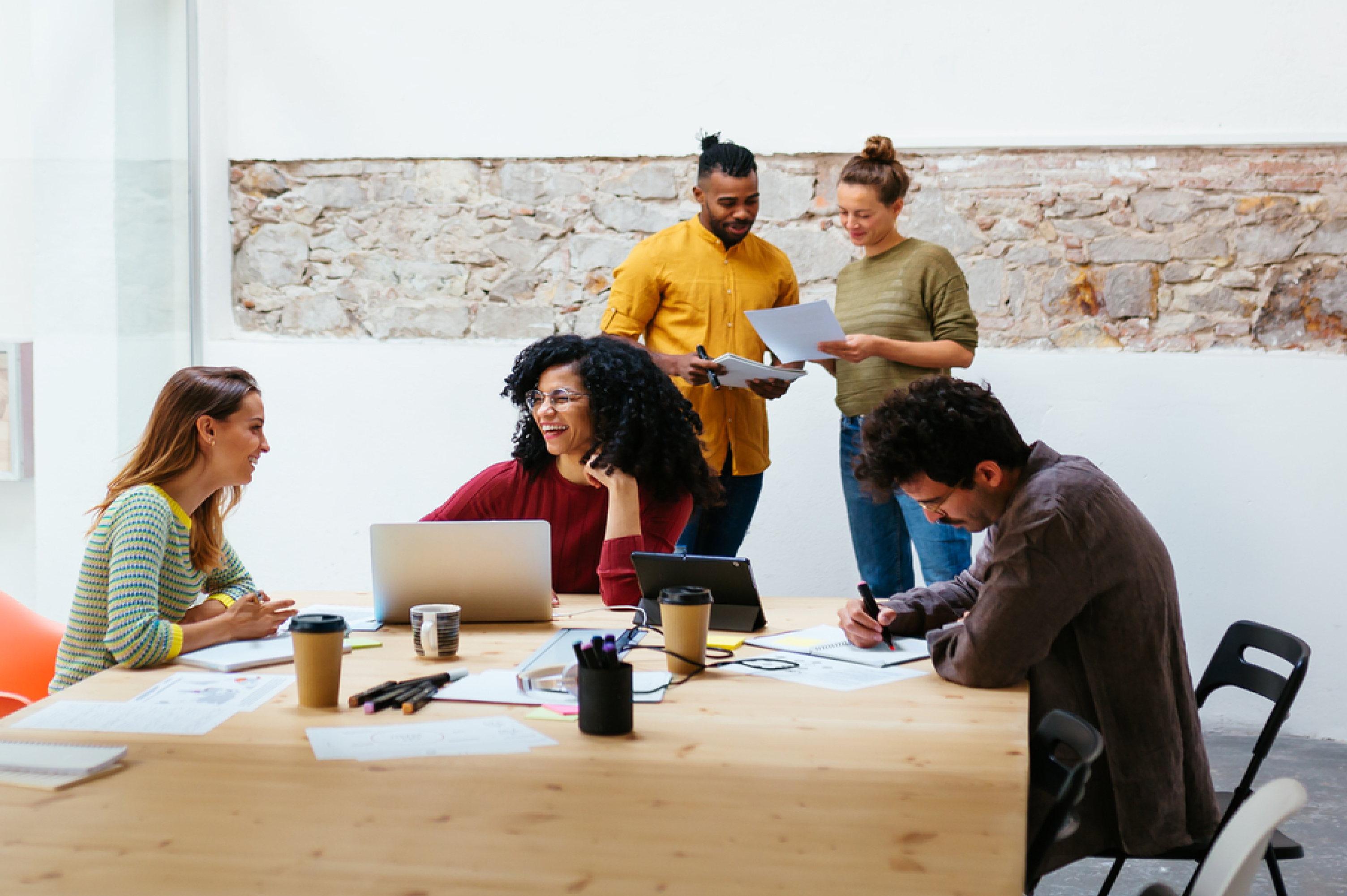 A diverse group of individuals discussing and collaborating in a well-lit meeting room.