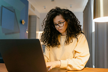 Woman in yellow sweater works at her laptop