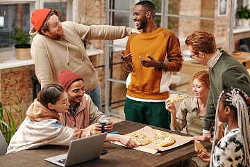 Gen Z employees enjoy pizza during a work meeting.