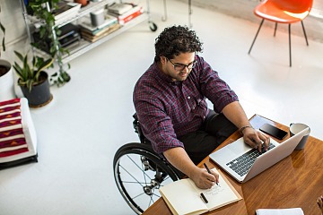 An overhead photo of an employee in a wheelchair working on their laptop